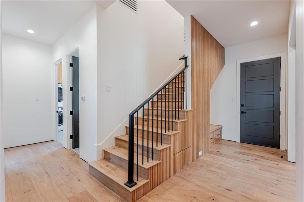1014 Chaparrel Lane Graford, TX 76449 - Photo 26 of 40 Stylish Staircase to the Upstairs Retreat - Tucked just inside as you enter from the garage, this sleek staircase leads to the upstairs retreat—home to the bunk room and additional flex space. Thoughtfully integrated beneath the stairs are built-in drawers and a place to hang you coats and hats, combining function with design. Slatted wood paneling adds architectural warmth, making this transition space as smart as it is stylish.