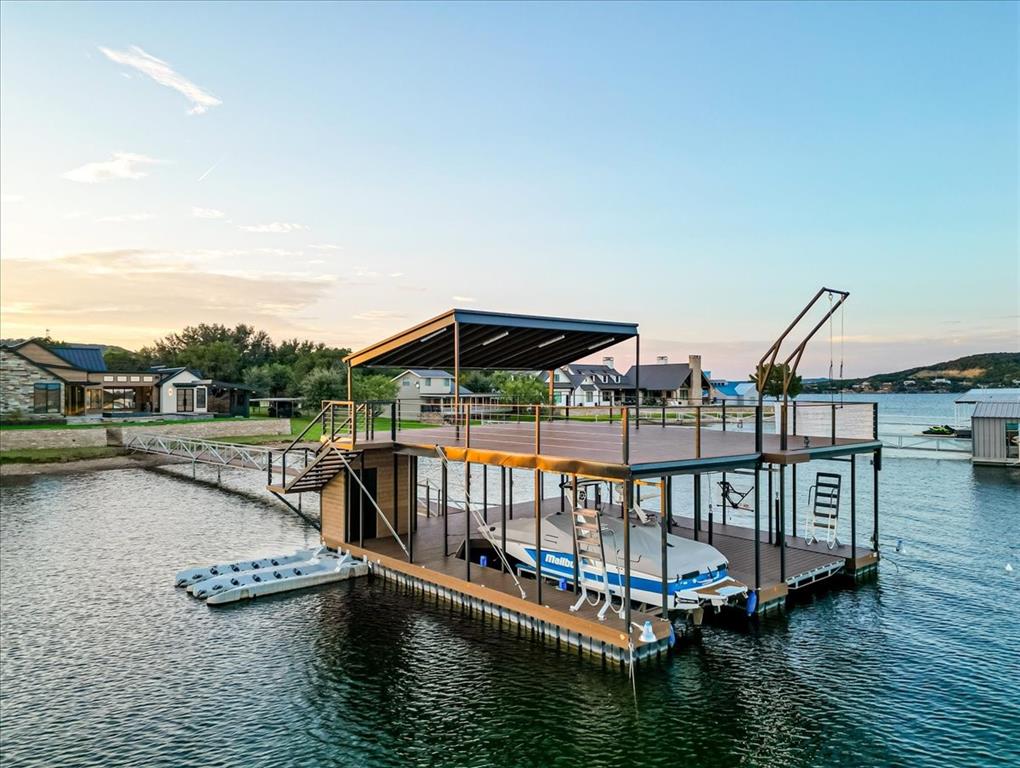 1014 Chaparrel Lane Graford, TX 76449 - Photo 36 of 40 Multi-Use Dock with Storage, Power, and Play - This thoughtfully designed dock blends practical function with lakefront fun. A steel-clad storage room matches the home’s aesthetic and is plumbed for water—ready for an ice maker if desired. A built-in freshwater power washer makes cleanup a breeze. The HydroHoist lift keeps your boat protected, while adjacent floating platforms accommodate PWCs. A rooftop lounge offers elevated lake views, and the main level includes a diving board, swing, fish feeder, and ample shaded space that can be lowered into the water for relaxing or entertaining. Purpose-built and play-ready, this dock is your all-day lakefront destination.