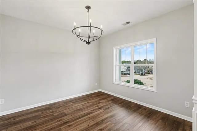 a view of an empty room with wooden floor and window
