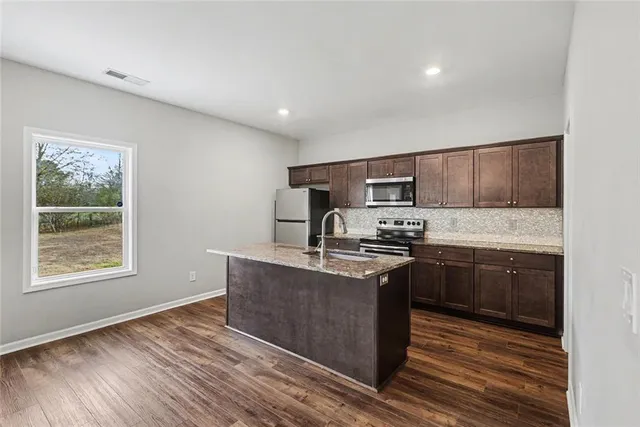 a kitchen with stainless steel appliances granite countertop a stove a sink and a microwave