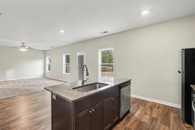 a kitchen with granite countertop a sink and dishwasher with wooden floor