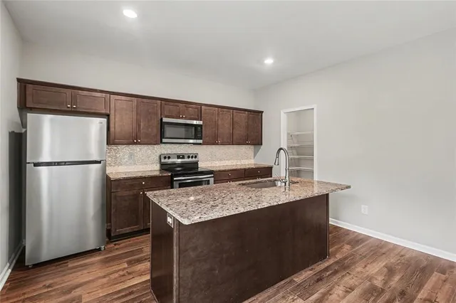 a kitchen with stainless steel appliances granite countertop a refrigerator a stove a sink and a microwave