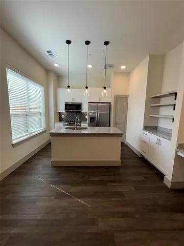 a kitchen with kitchen island stainless steel appliances a large counter top and a wooden floor