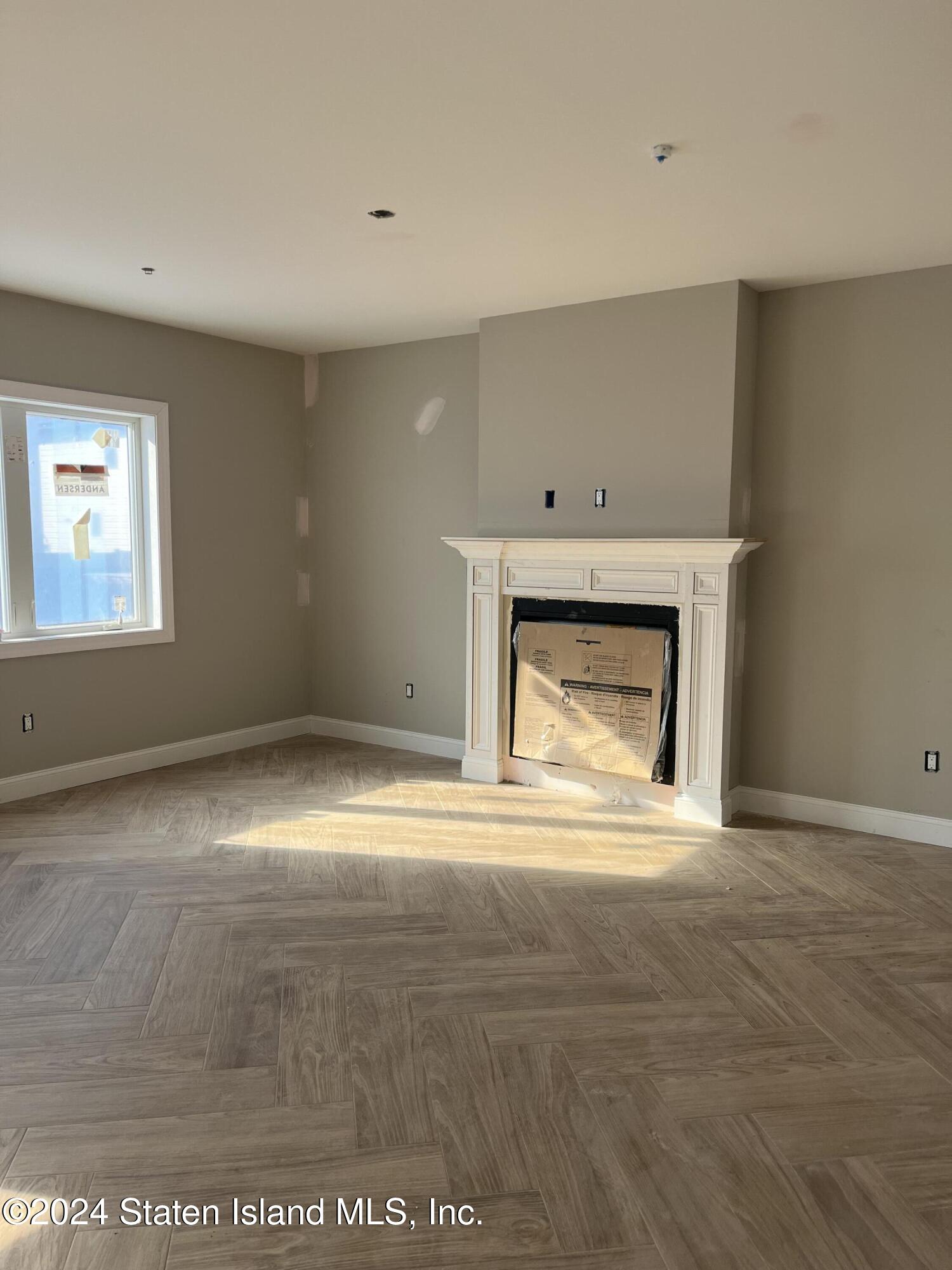 3474 Richmond Road Staten Island, NY 10306 - Photo 6 of 9 an empty room with a fireplace and wooden floor