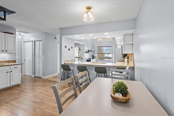 a living room with stainless steel appliances furniture a rug and a kitchen view
