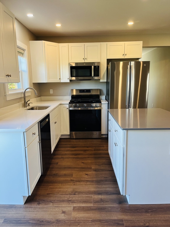 a large kitchen with wooden floor and stainless steel appliances