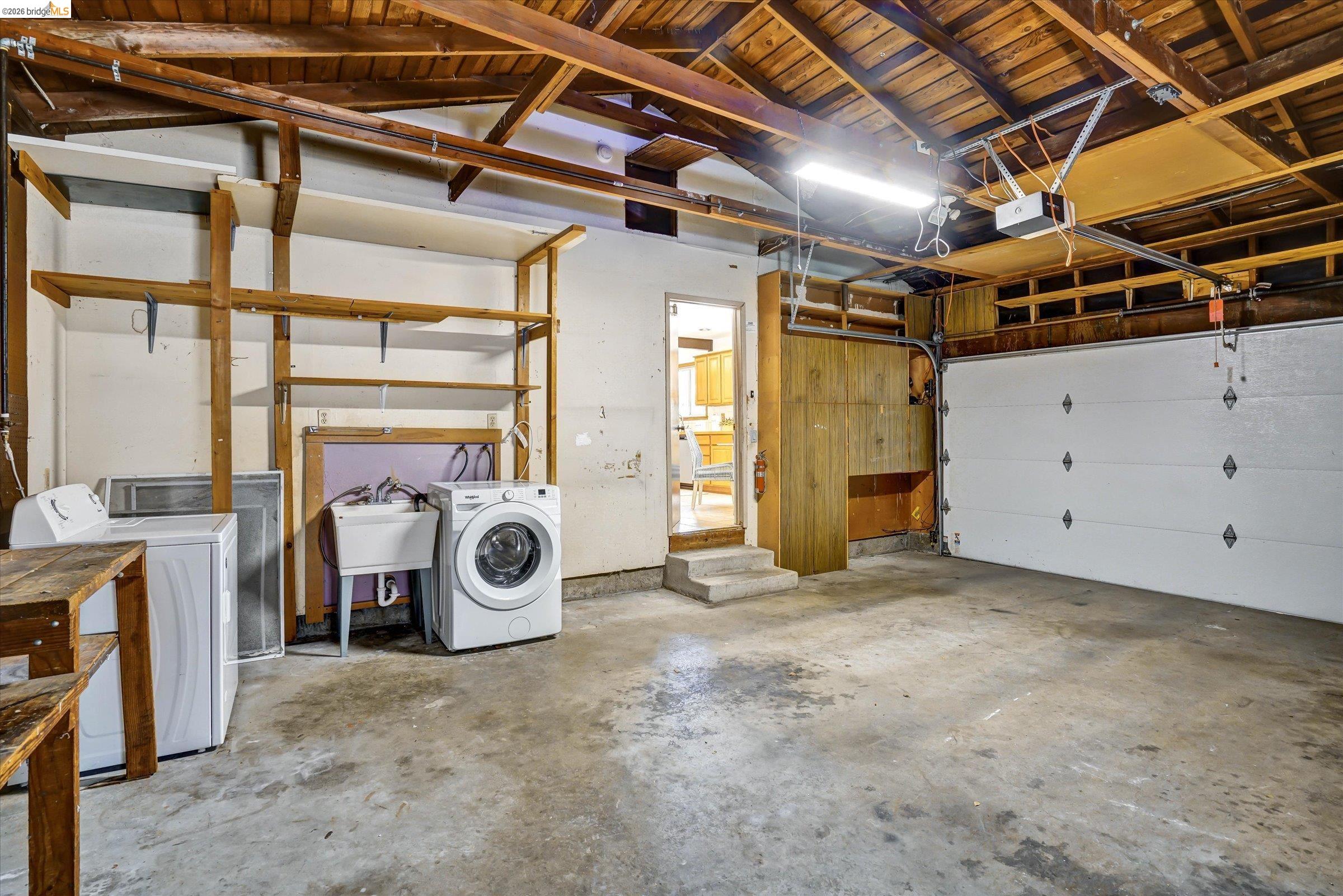 2826 Wright Avenue Pinole, CA 94564 - Photo 49 of 70 Two-car garage with exposed wood beam ceiling, concrete flooring, built-in shelving, and utility sink