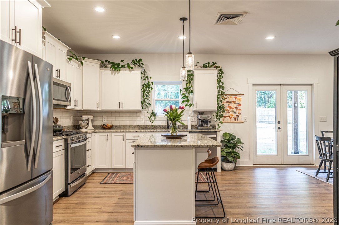 480 Clark Street Southern Pines, NC 28387 - Photo 7 of 28 a kitchen with stainless steel appliances granite countertop a refrigerator a sink dishwasher a stove and white cabinets with wooden floor