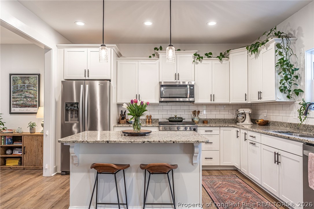 480 Clark Street Southern Pines, NC 28387 - Photo 8 of 28 a kitchen with stainless steel appliances kitchen island granite countertop a refrigerator a stove a sink dishwasher and white cabinets with wooden floor