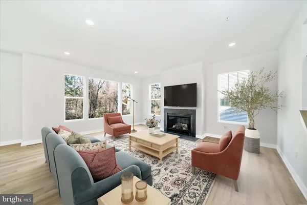 an empty room with wooden floor fireplace and windows