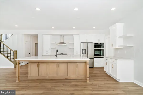 a large white kitchen with stainless steel appliances granite countertop a stove and a sink
