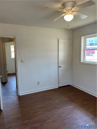 an empty room with wooden floor and a chandelier fan