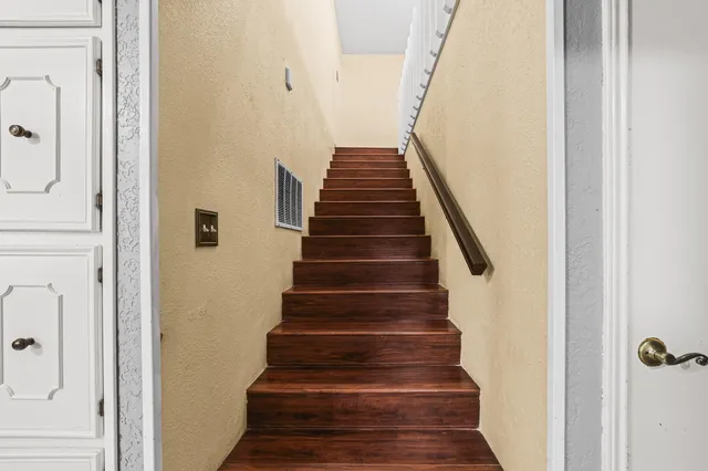 a view of staircase with wooden floor and white walls