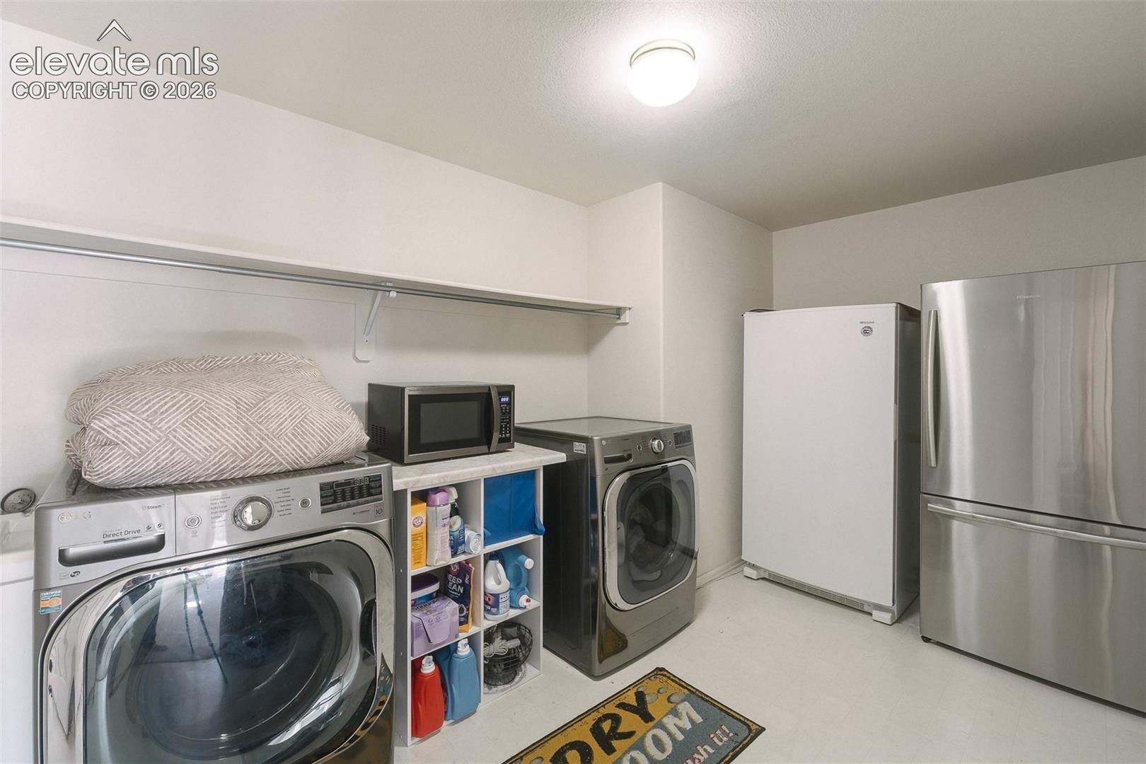 7869 Fort Smith Road Peyton, CO 80831 - Photo 31 of 50 Basement Laundry Room with built-in shelf, washer, dryer, stand up freezer, and stainless steel refrigerator that stays.