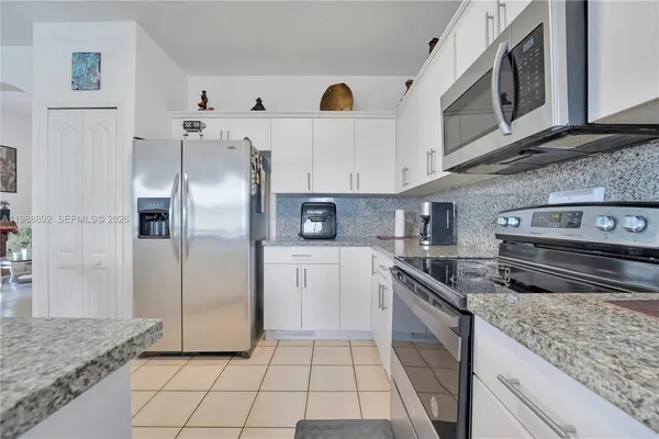 a kitchen with stainless steel appliances granite countertop a refrigerator a stove and a sink