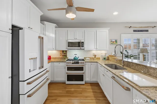 a kitchen with granite countertop a sink stainless steel appliances and cabinets