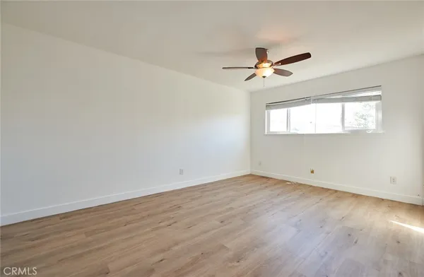 an empty room with wooden floor ceiling fan and windows