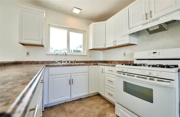 a kitchen with granite countertop white cabinets and white appliances