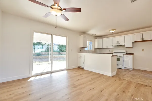 a kitchen with stainless steel appliances granite countertop a refrigerator a sink dishwasher a stove and white countertops with wooden floor