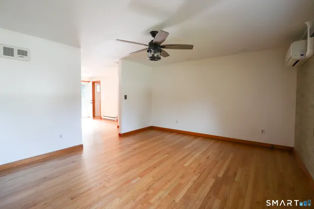 a view of empty room with wooden floor fireplace and a window