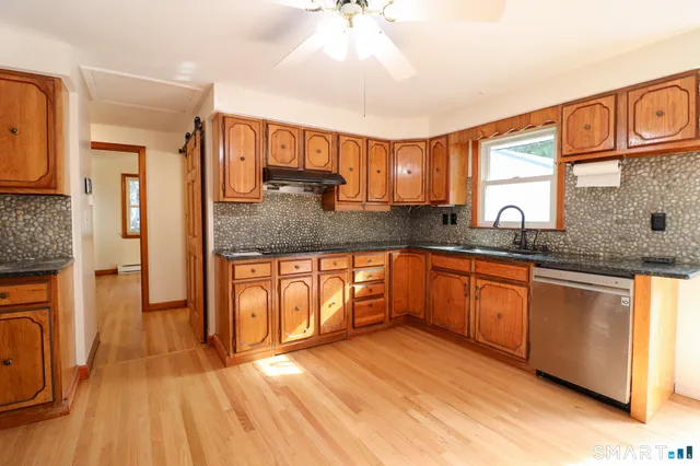 an empty room with wooden floor a ceiling fan and windows