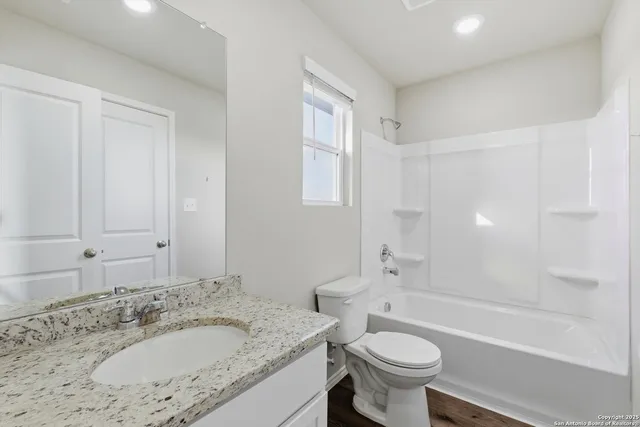 a bathroom with a granite countertop sink a toilet a mirror and bathtub