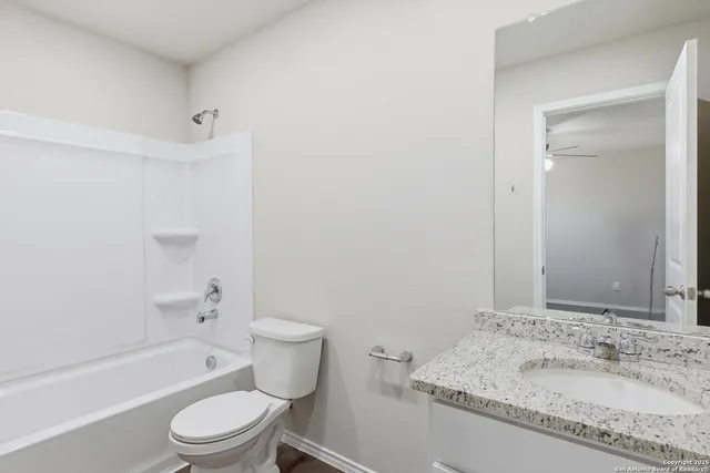 a bathroom with a granite countertop sink a toilet and shower