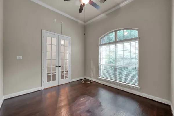 an empty room with wooden floor chandelier fan and windows