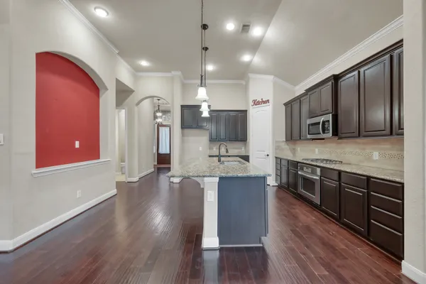 a large kitchen with stainless steel appliances wooden floors and wooden cabinets