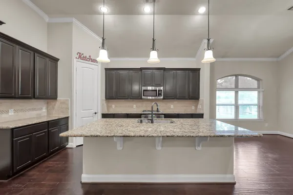 a large kitchen with granite countertop a sink a counter space appliances and cabinets