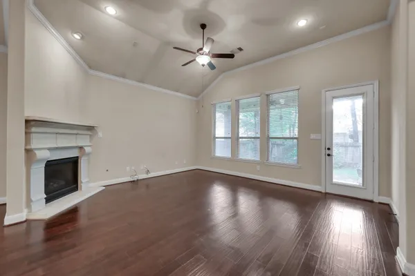 a view of an empty room with wooden floor fireplace and a window
