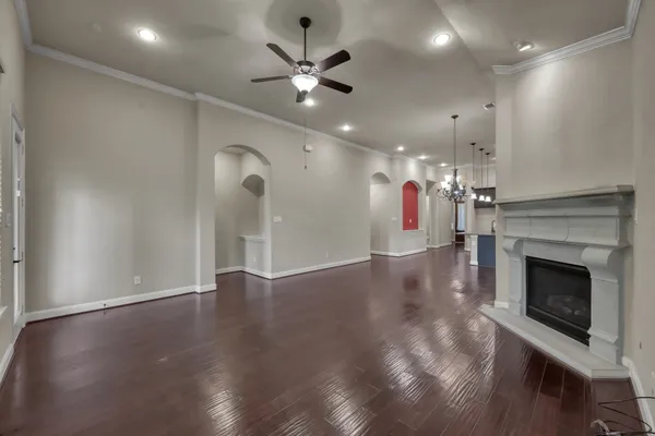 an empty room with wooden floor fireplace and ceiling fan