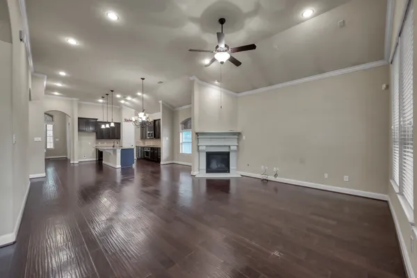 a view of a kitchen and an empty room with wooden floor and a kitchen