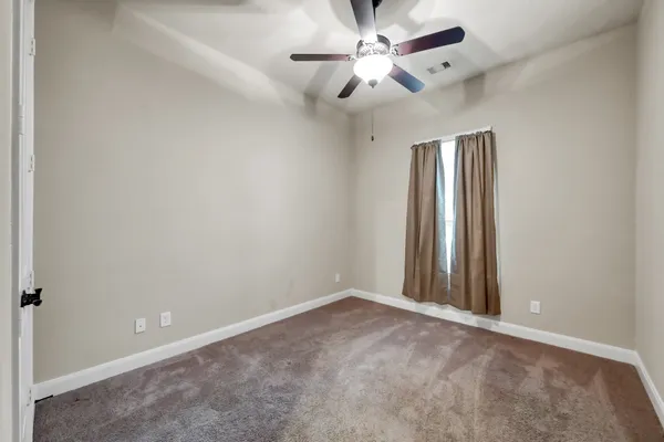 an empty room with a fan & a ceiling fan