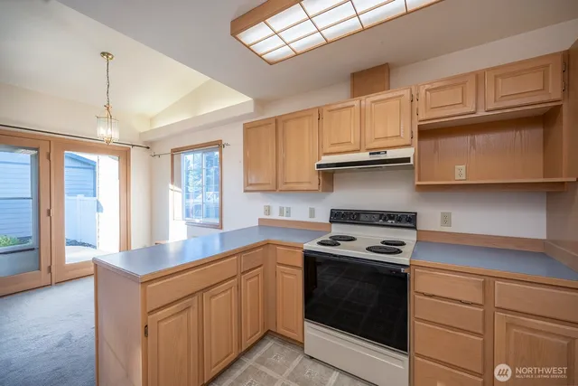 a kitchen with granite countertop stainless steel appliances a stove sink and cabinets