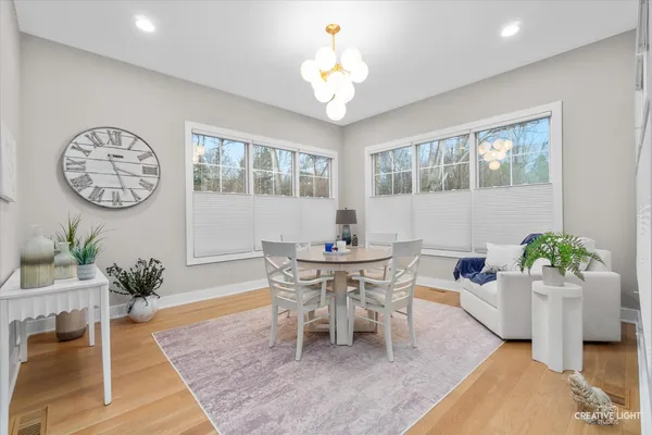 a dining room with wooden floor a chandelier a wooden table and chairs