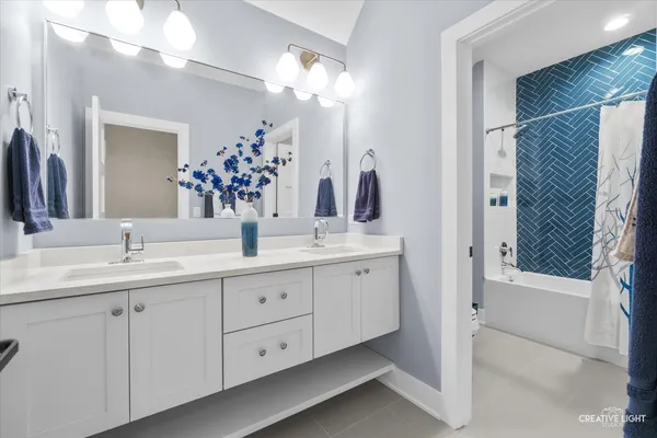 a bathroom with a double vanity sink mirror and bathtub