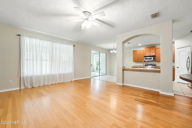 a view of a dining room and livingroom with furniture wooden floor a chandelier