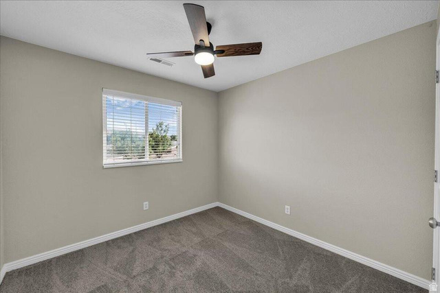 3155 South Hidden Dr Street, Unit 248 St. George, UT 84790 - Photo 12 of 24 Room featuring neutral-toned walls, gray carpet, a single window with white blinds, and a dark wood ceiling fan with integrated lighting