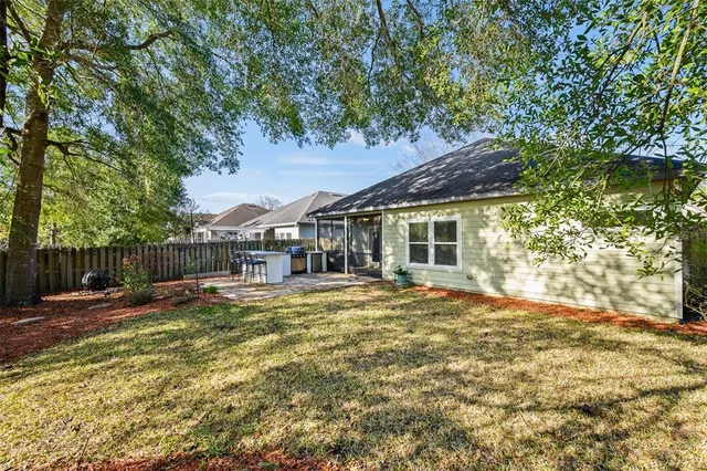 a backyard of a house with table and chairs under an umbrella