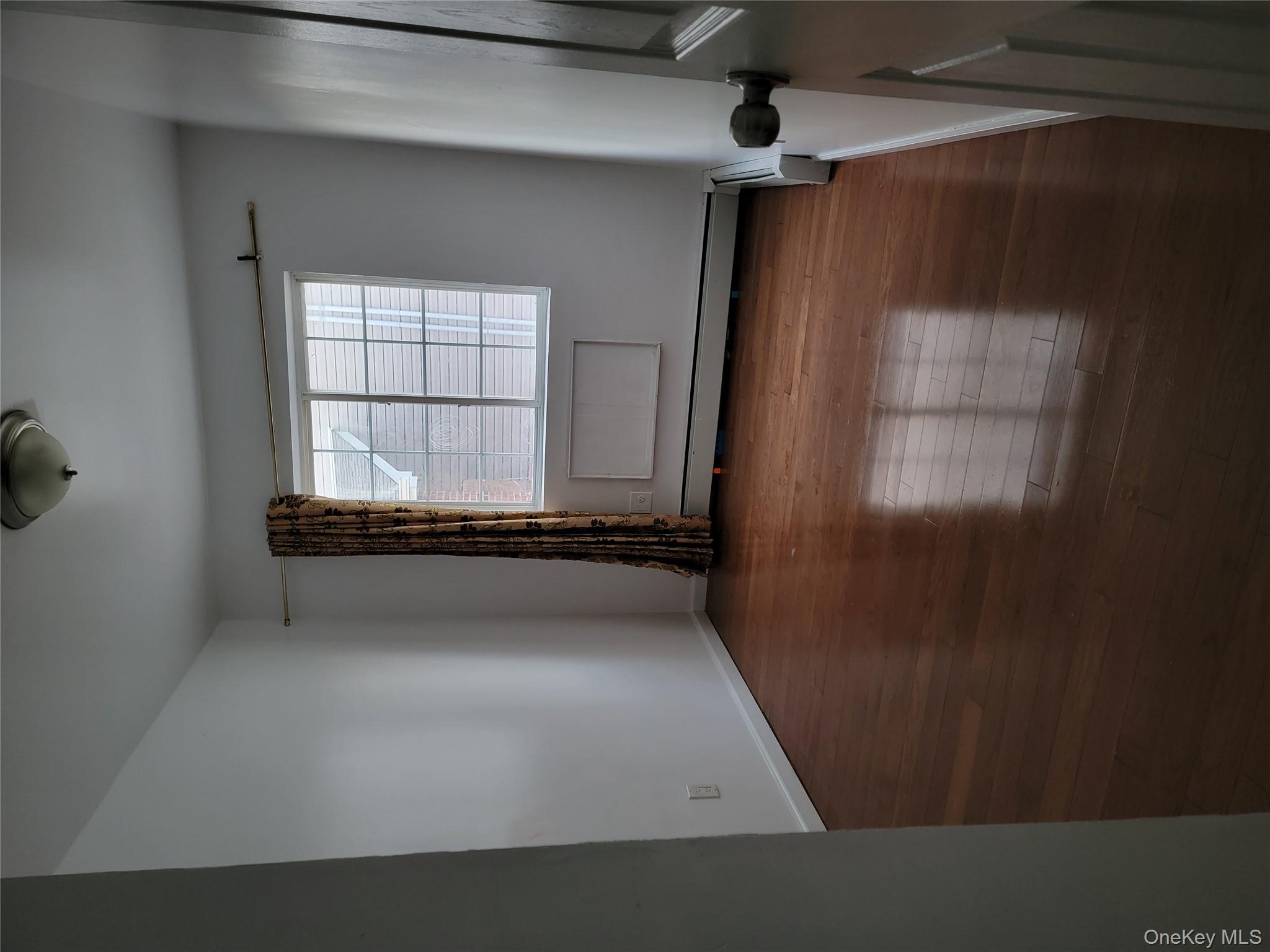 69-06 Beach Channel Drive Queens, NY 11692 - Photo 4 of 15 an empty room with wooden floor and windows