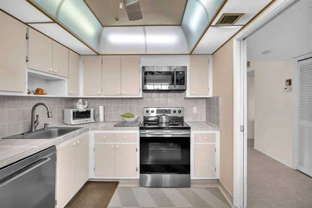 a kitchen with stainless steel appliances granite countertop a refrigerator a sink dishwasher a dining table and chairs with wooden floor