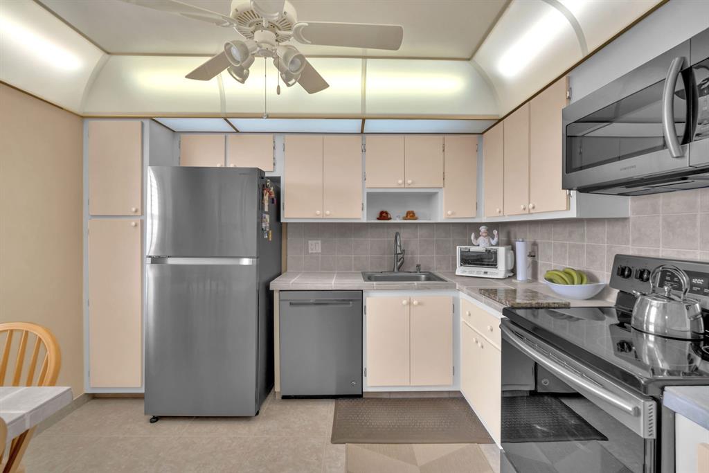 605 Oaks Drive, Unit 907 Pompano Beach, FL 33069 - Photo 4 of 41 a kitchen with stainless steel appliances granite countertop a refrigerator a sink dishwasher a stove and white cabinets with wooden floor