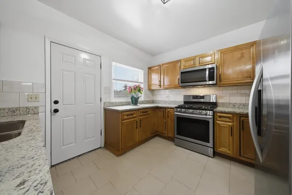 a kitchen with stainless steel appliances granite countertop a refrigerator a stove top oven a sink and dishwasher