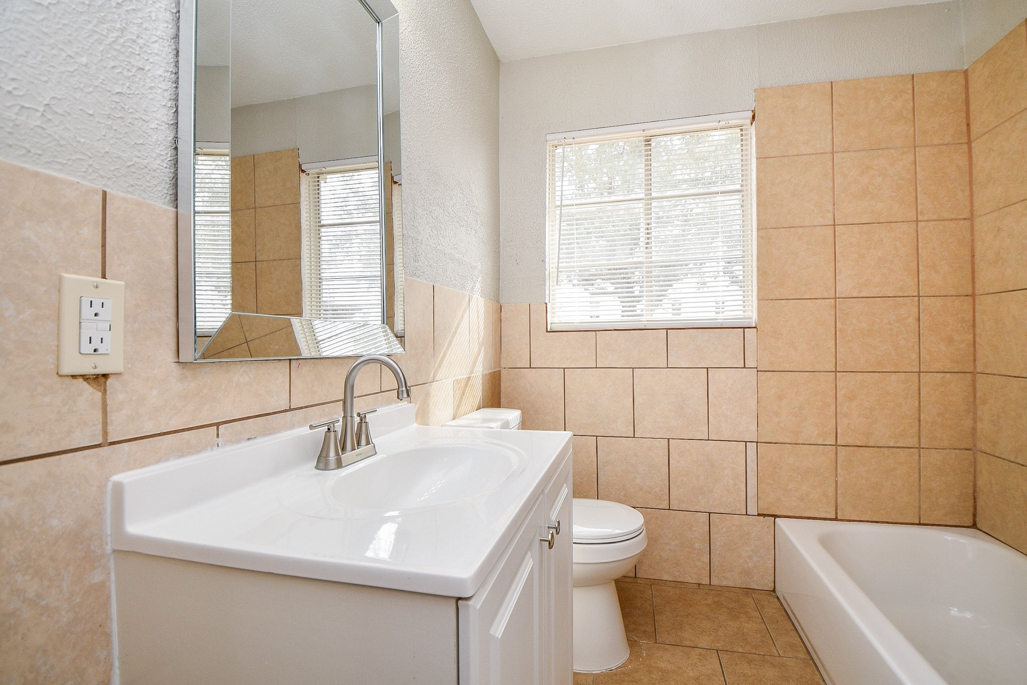 1606 Harris Avenue Pasadena, TX 77506 - Photo 13 of 20 Bathroom features a sleek vanity with a large mirror, a bathtub, and a window for natural light.