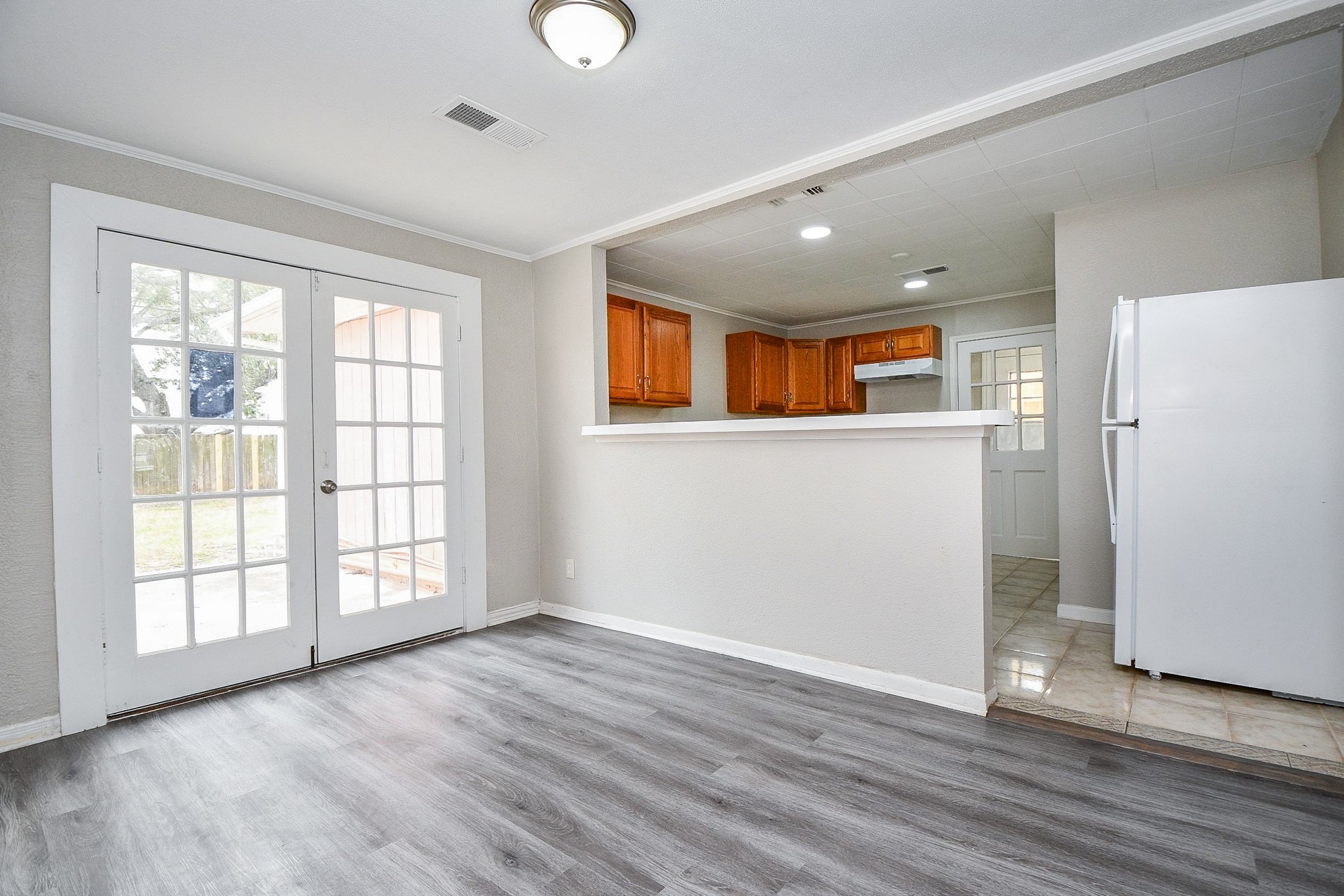 1606 Harris Avenue Pasadena, TX 77506 - Photo 9 of 20 Bright, airy kitchen with open layout, laminate wood flooring, breakfast bar, French doors, light wood cabinets, and white gas stove.