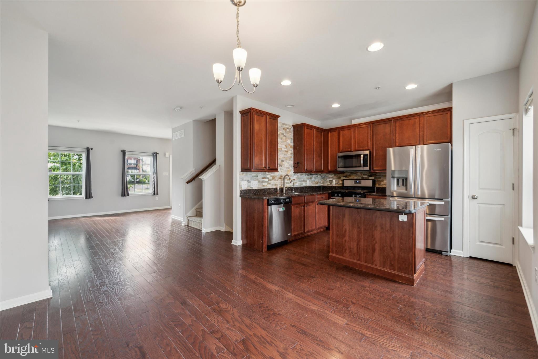 3799 Jacob Stout Road, Unit 5 Doylestown, PA 18902 - Photo 3 of 25 a kitchen with stainless steel appliances granite countertop a refrigerator a sink dishwasher a stove and a dining table with wooden floor