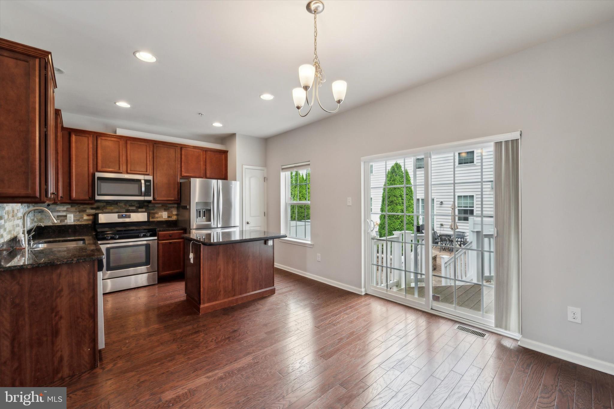 3799 Jacob Stout Road, Unit 5 Doylestown, PA 18902 - Photo 4 of 25 a open kitchen with stainless steel appliances granite countertop a stove top oven a refrigerator with wooden floors and couches