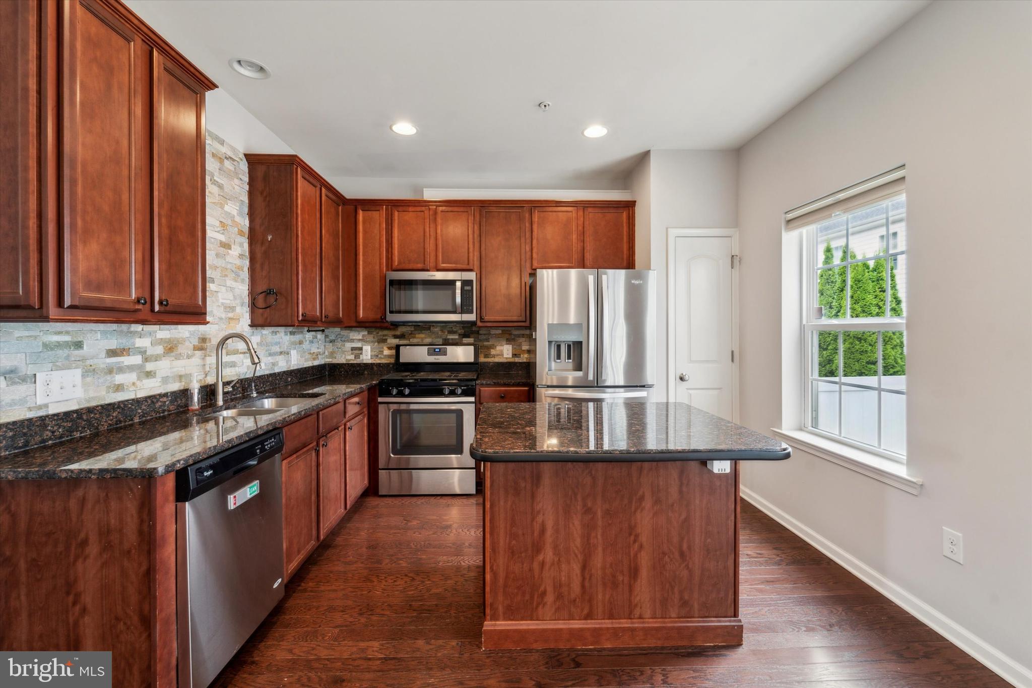 3799 Jacob Stout Road, Unit 5 Doylestown, PA 18902 - Photo 5 of 25 a kitchen with kitchen island granite countertop wooden floors stainless steel appliances a sink and a window