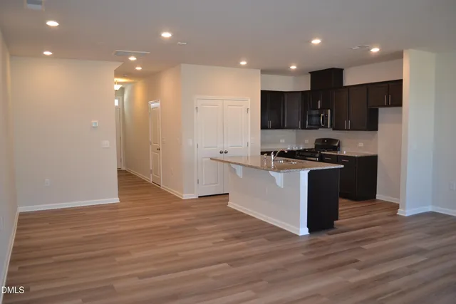 a large kitchen with stainless steel appliances granite countertop a stove a sink and a refrigerator with wooden floor